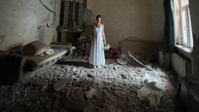 Тъжна жена с булчинска рокля стои абсолютно неподвижно в разрушен