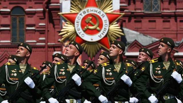 Московчани наблюдават руските военни машини които се движат пред катедралата