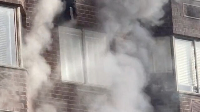 Пожарникари жена която виси от прозорец на в Ню Йорк
