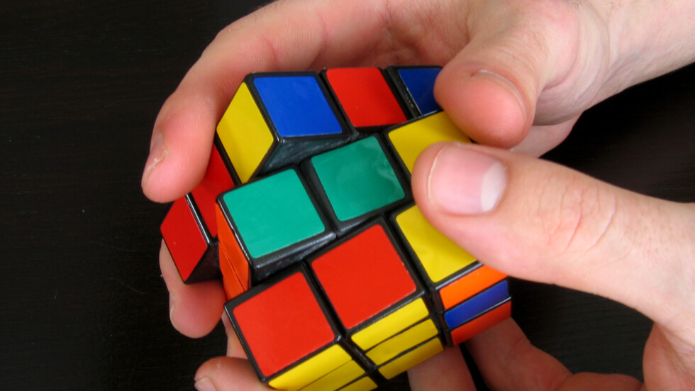 Студент подрежда три кубчета на Рубик, докато жонглира с тях